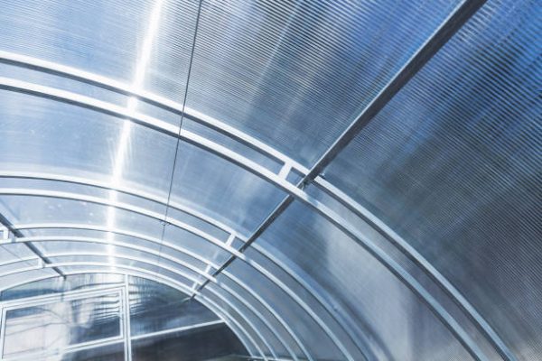 Modern greenhouse structure. Polycarbonate roof mounted on double arched steel frame